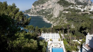 Ein Resort mit Pool, Liegestühlen und Blick auf Meer und Berge.