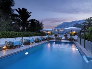 Una piscina al aire libre, sombrillas, sillones reclinables de piscina