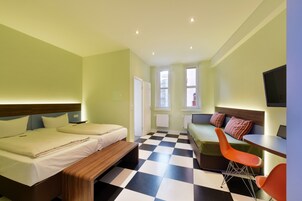Una habitación de hotel con dos camas, un sofá, una mesa de comedor y un televisor.