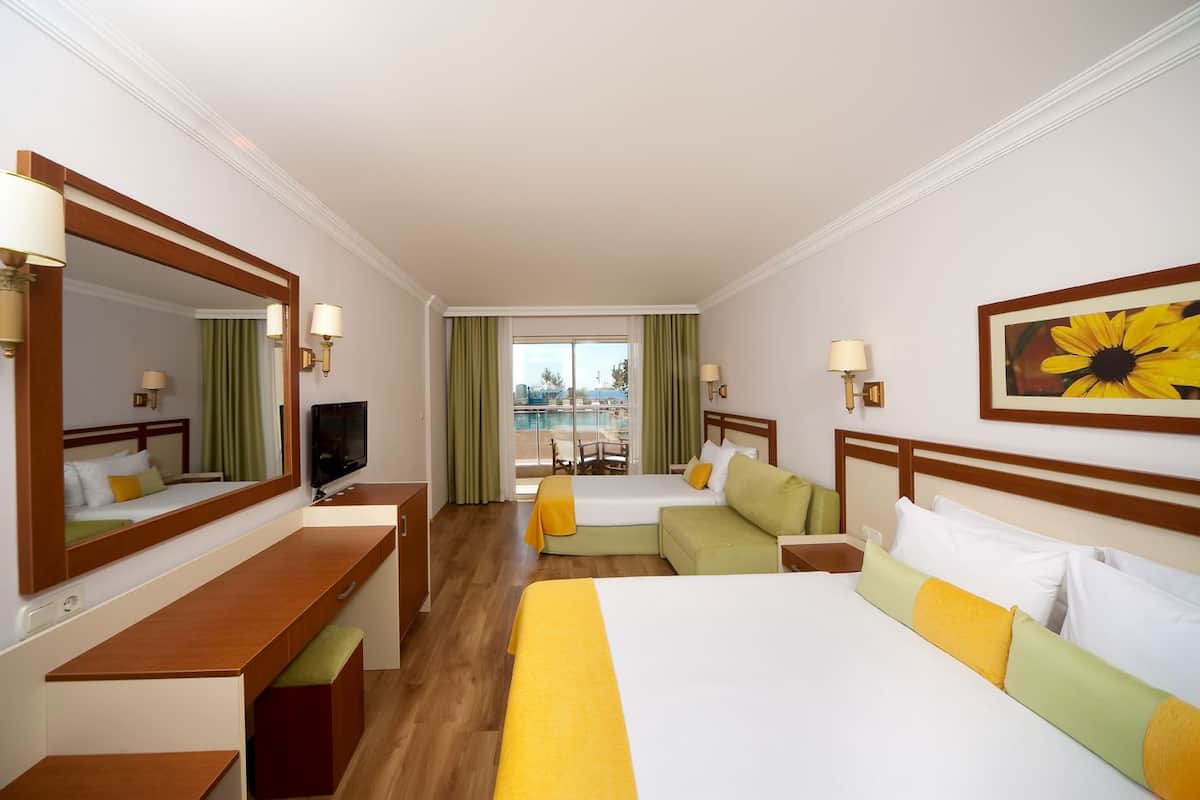 Habitación de hotel con cama, escritorio, televisión y vistas a una piscina y al paisaje urbano.