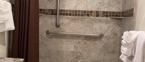 A bathroom with a shower, toilet, and a towel rack.