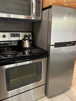 Cozinha equipada com micro-ondas, forno e frigorífico de aço inoxidável.
