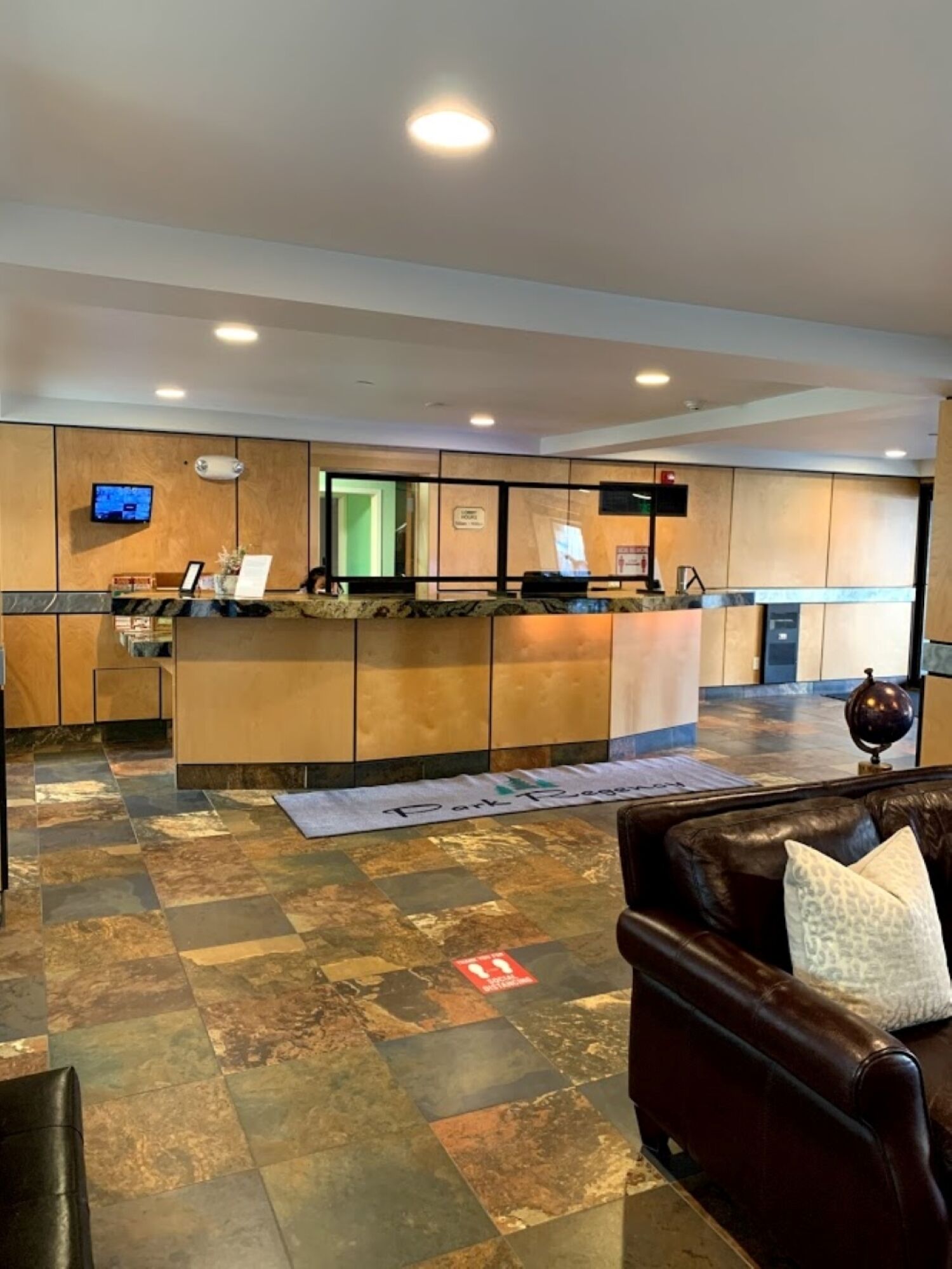 A hotel reception area with a reception desk, a television, and a sign indicating a parking area.