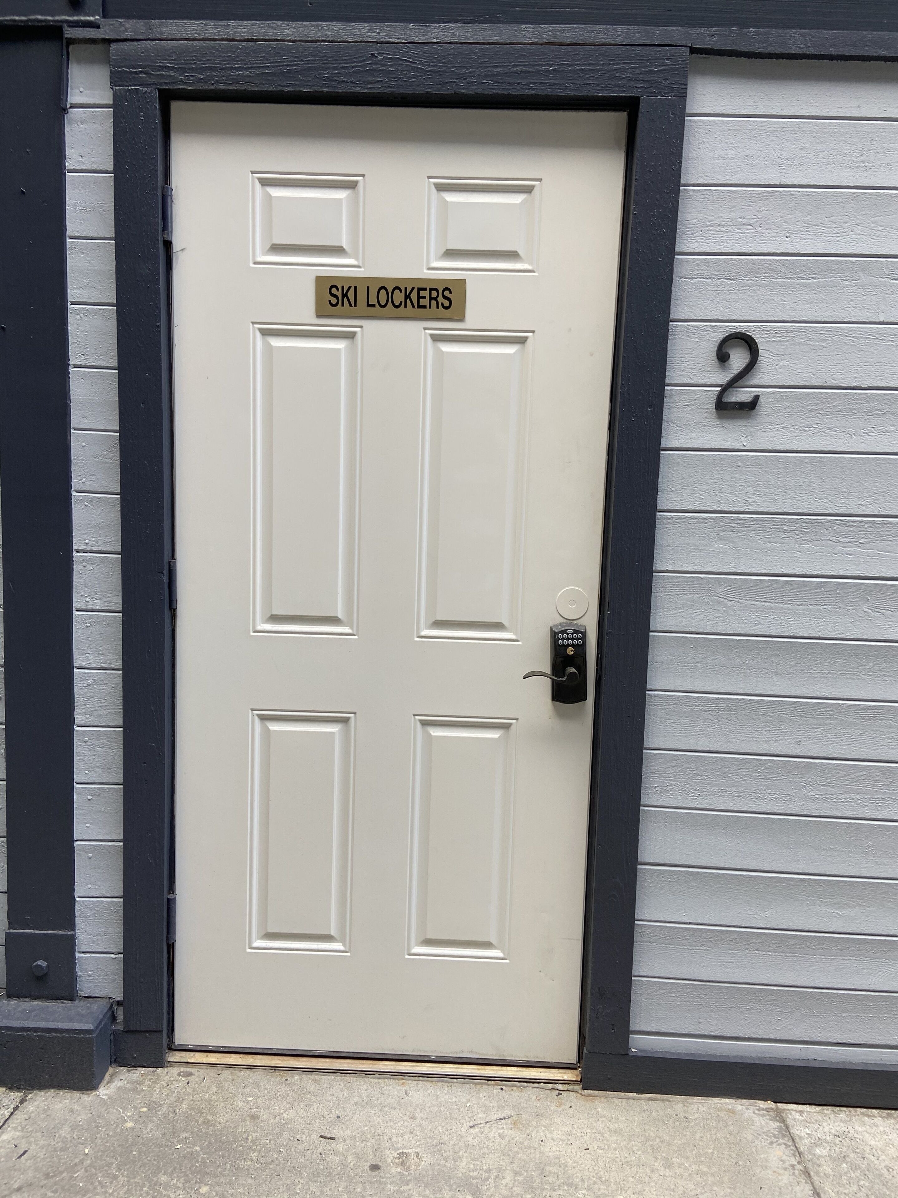 Eine Tür mit einem Schild, auf dem „SKIL LOCKERS“ steht, und der Zahl 2 an der danebenliegenden Wand.