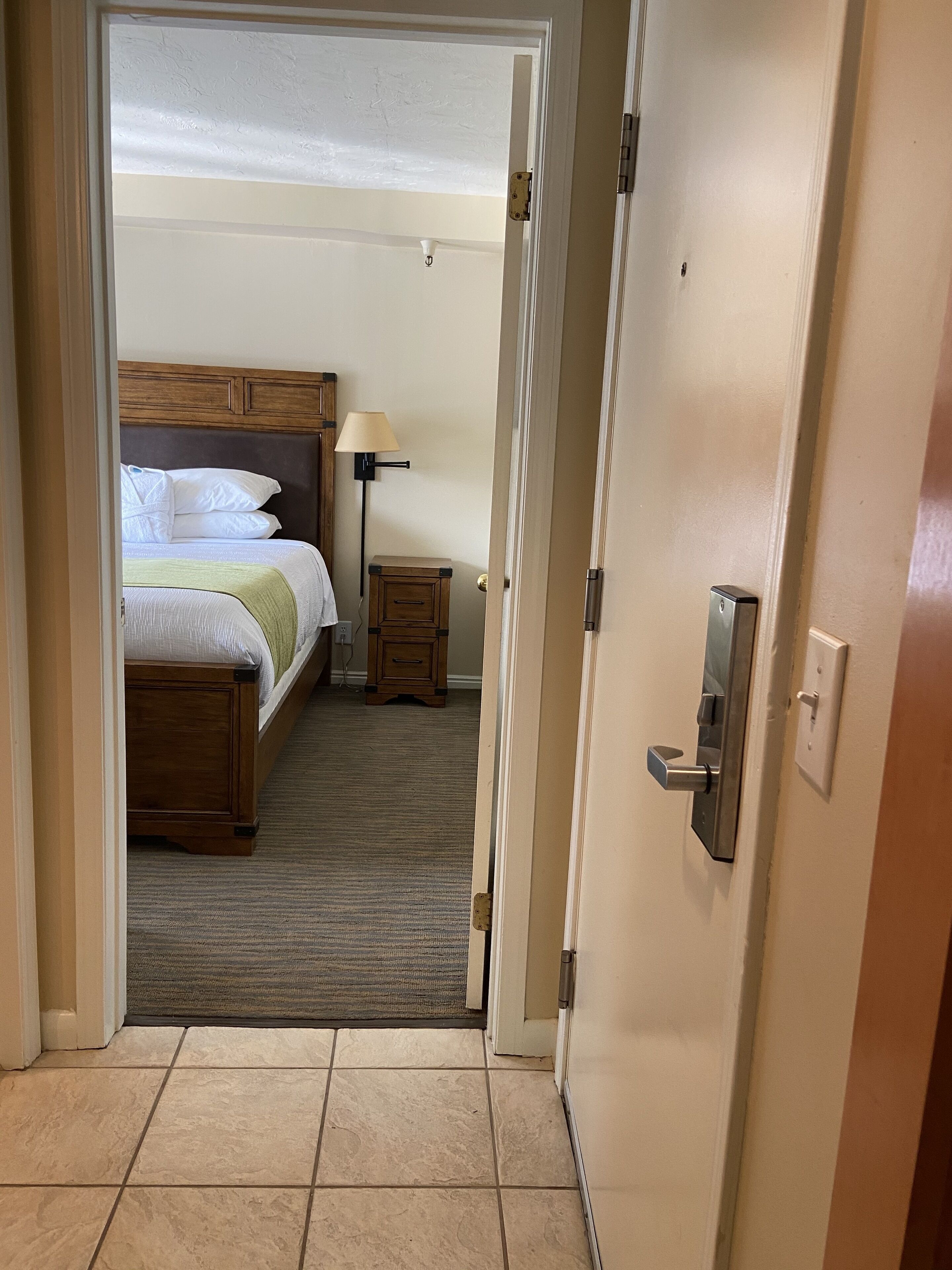 A hotel room with a bed, bedside lamp, and a small nightstand.