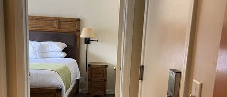 A hotel room with a bed, bedside lamp, and a small nightstand.