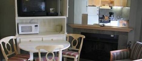 A compact living space with a dining area, a kitchenette, and a fireplace.