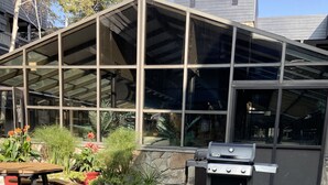 An outdoor patio with a grill, seating, and potted plants.
