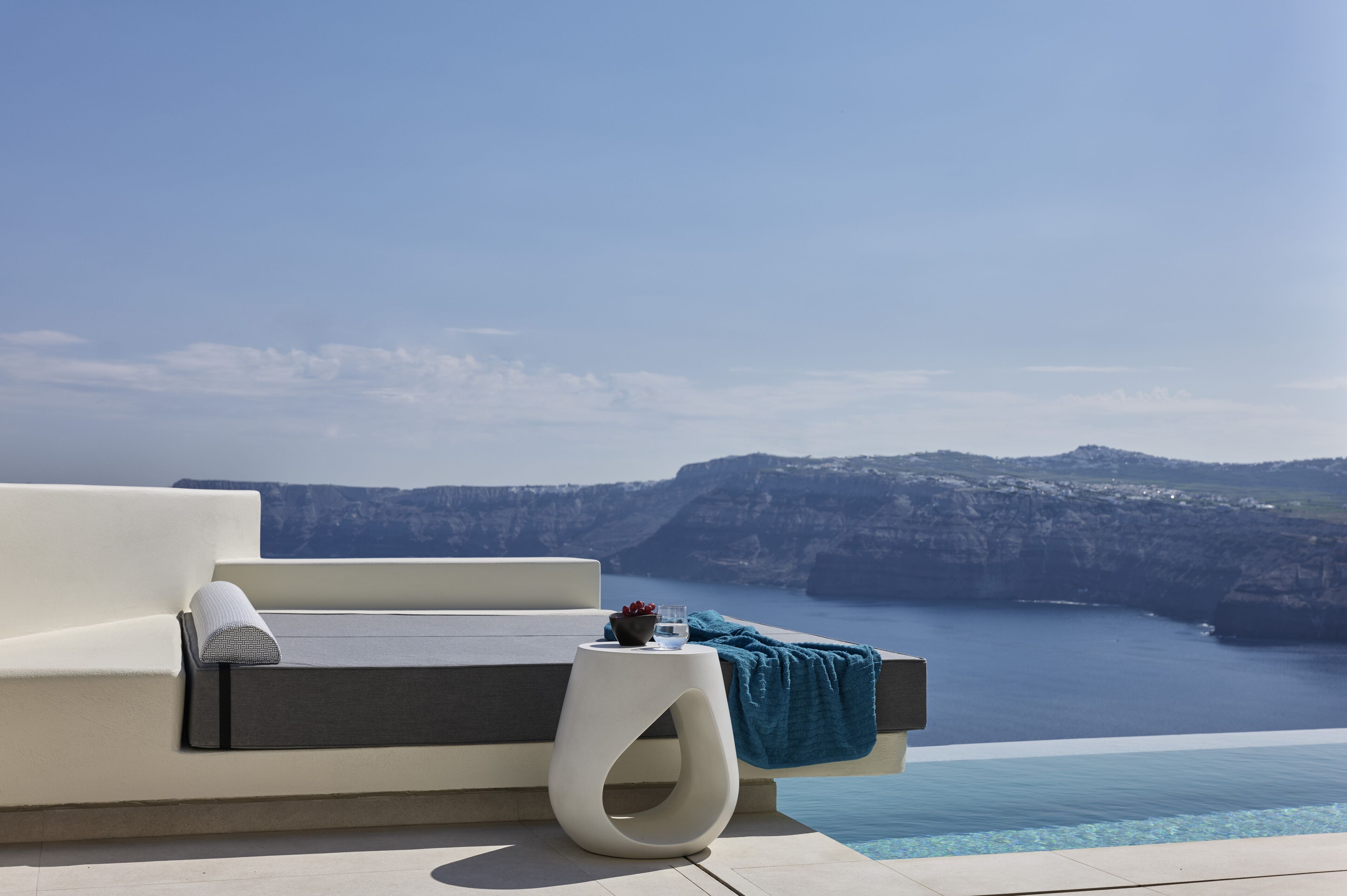 Un área de estar moderna al aire libre con piscina y vistas panorámicas al acantilado.