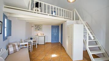 Une chambre spacieuse aménagée en loft, avec une mezzanine, une petite kitchenette et un escalier.