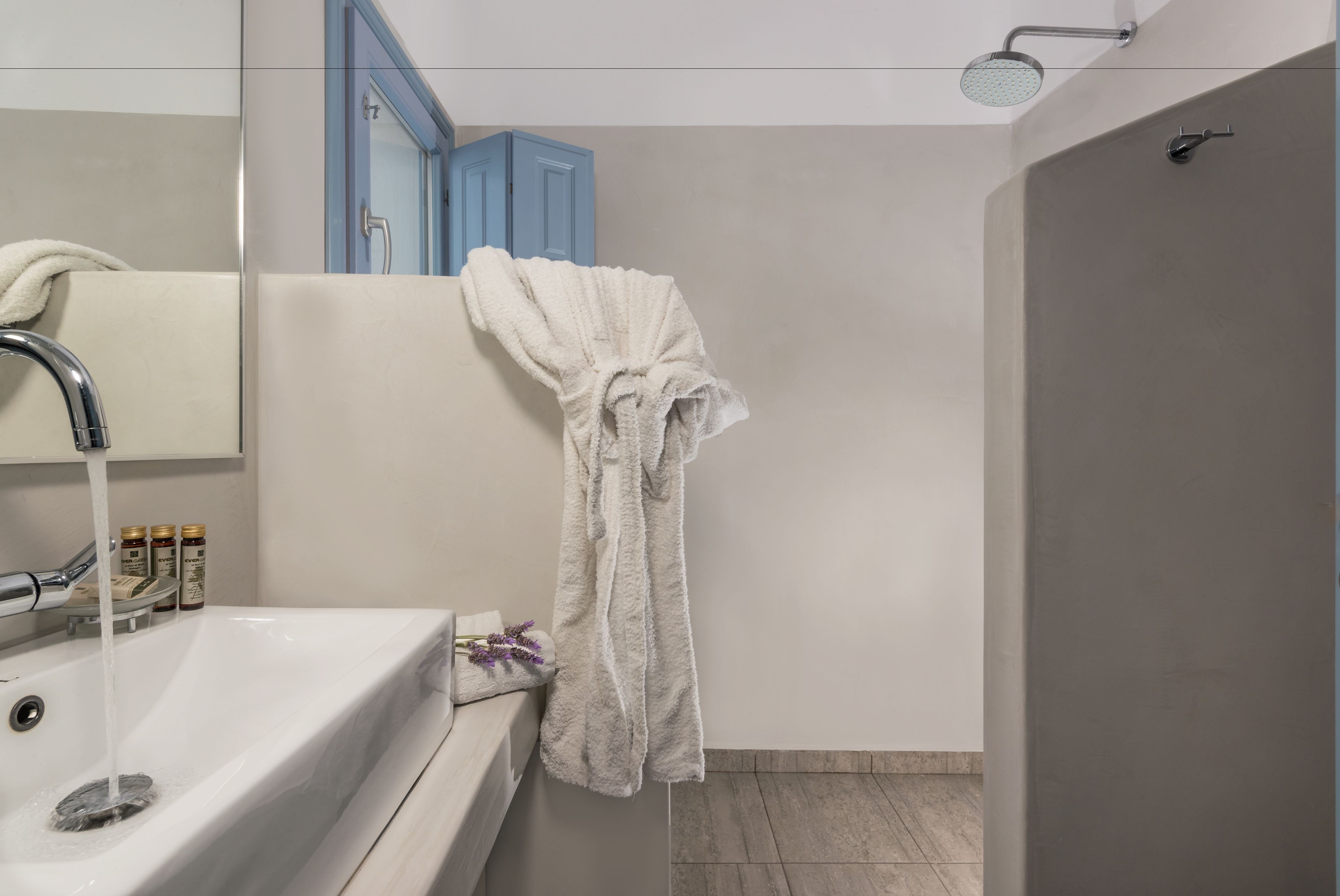 Ein Badezimmer mit einem weißen Waschbecken, einem Handtuch, das an der Wand hängt, und einer Duschbrause.