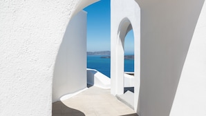 A white-walled corridor with a view of the sea and distant land. - Apanemo Hotel (Santorini)