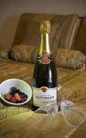 A bottle of Taittinger champagne, a bowl of mixed berries, and two empty wine glasses on a patterned tablecloth. - Hotel Castlepollard (Castlepollard)