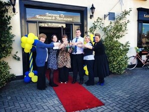 A group of people standing in front of a building with a sign that reads "Entrance To Reception & Restaurant". - Hotel Castlepollard (Castlepollard)