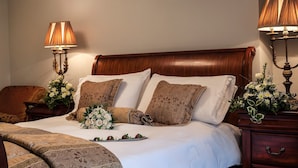 A neatly made bed with a floral arrangement, two bedside tables with lamps, and a wooden headboard.