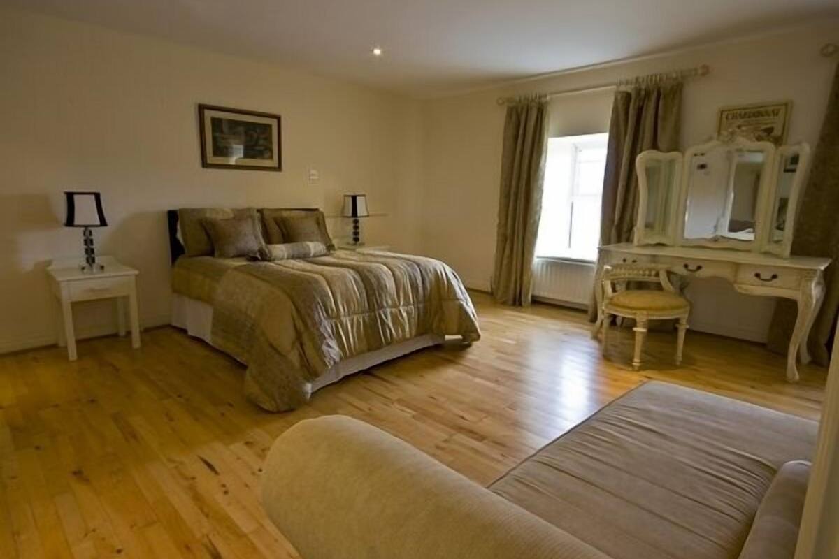 A bedroom with a bed, bedside tables, a dresser, a chair, and a window with curtains.