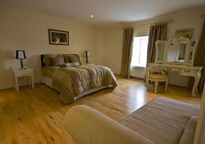 A bedroom with a bed, bedside tables, a dresser, a chair, and a window with curtains. - Hotel Castlepollard (Castlepollard)