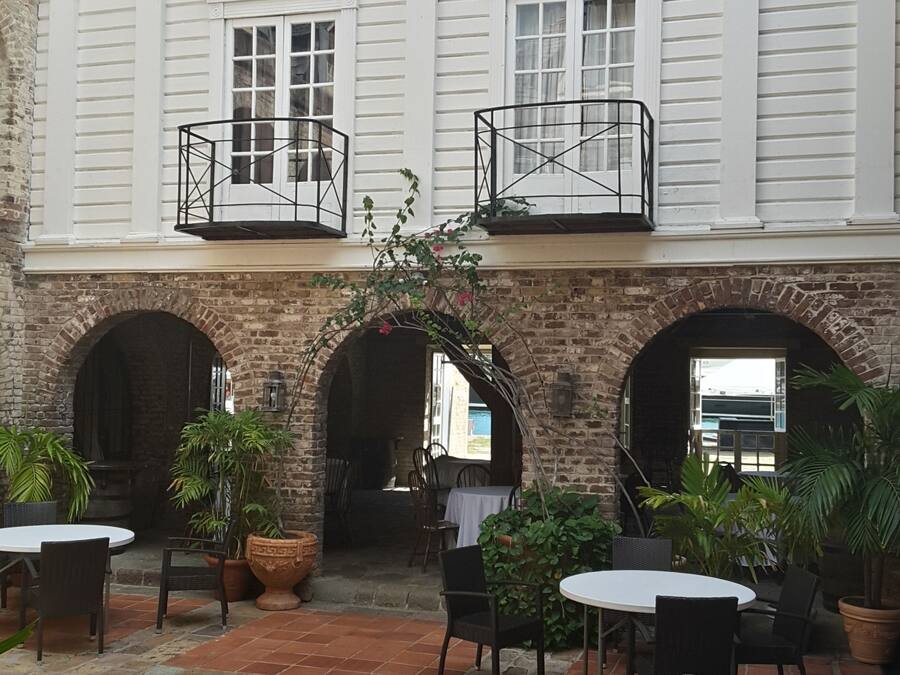 Ein Innenhof mit Backsteinfassade, einem Gebäude mit Balkonen und Außenbestuhlung.