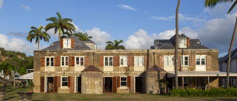 A two-story building with a brick facade, multiple windows with shutters, and a covered porch area.