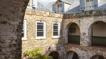 An architectural view of a courtyard with brick walls, arched windows, and a potted plant.