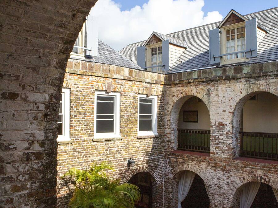 An architectural view of a courtyard with brick walls, arched windows, and a potted plant.