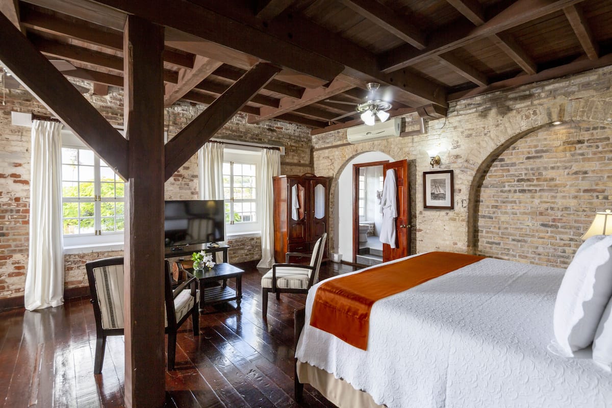 A room with a bed, wooden furniture, a television, and a brick wall.
