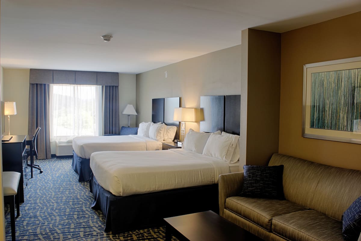 A hotel room with two beds, a sofa, a desk, and a chair.