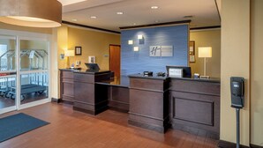 Zona de recepció d'hotel amb un disseny modern, que inclou un taulell de recepció, una estació de registre digital i vistes del vestíbul i els ascensors.