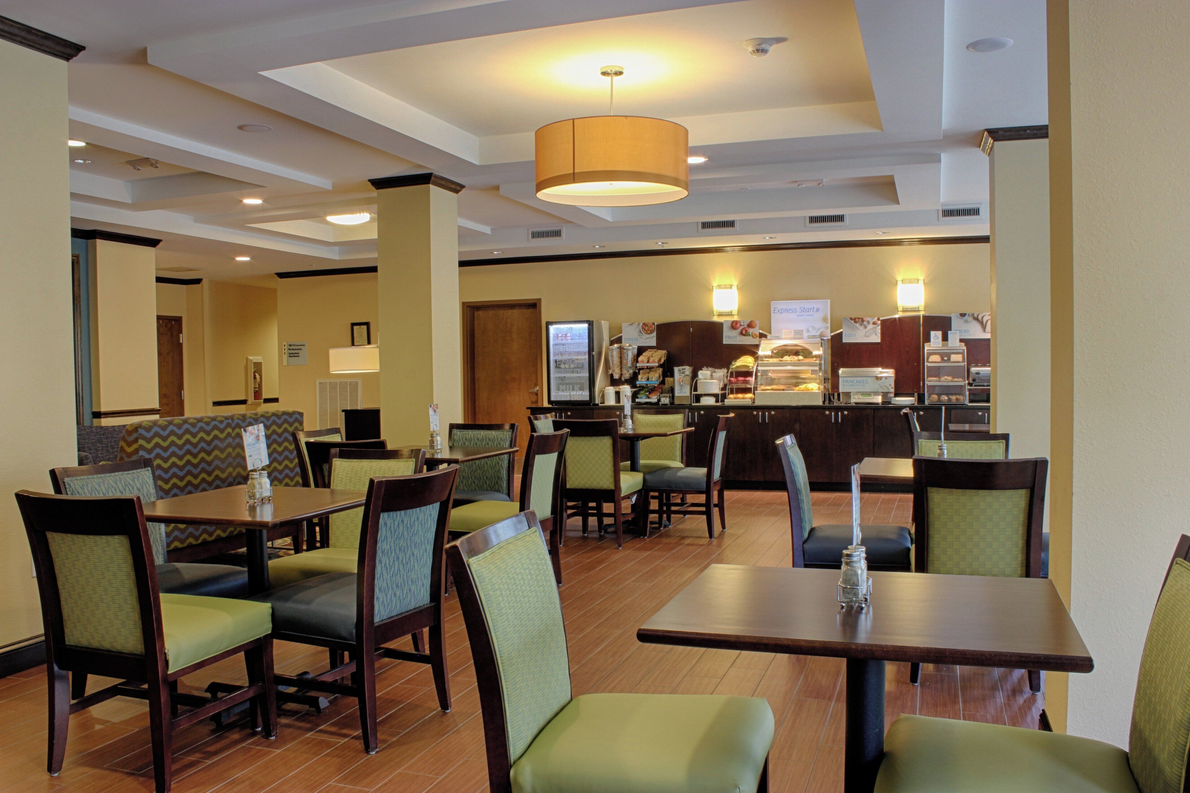 A hotel dining area with booths and tables, a breakfast bar, and a variety of food options.