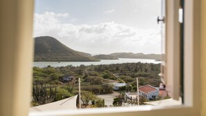 A view from a window overlooking a lake, surrounded by greenery and hills. - Landhuis klein Santa Martha (Soto)