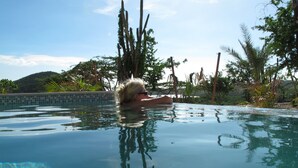 A person in a clear, calm pool with reflections of trees and a distant hill. - Landhuis klein Santa Martha (Soto)