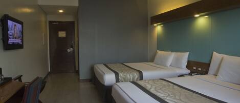 A hotel room with two beds, a desk, and a television.