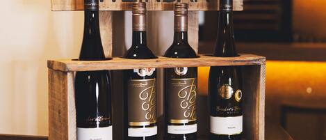 A wooden wine rack with four bottles of wine labeled 'Weinbar'.