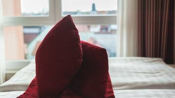 A bed with a red pillow and a white bedspread.