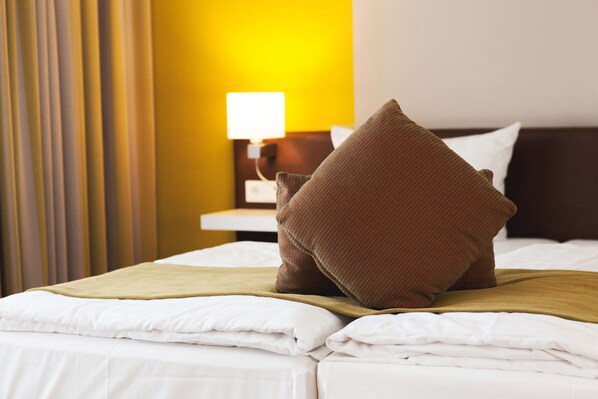 A neatly made bed with white linens, a brown throw blanket, and a brown pillow. - Weinhotel Kaisergarten (Alzey)