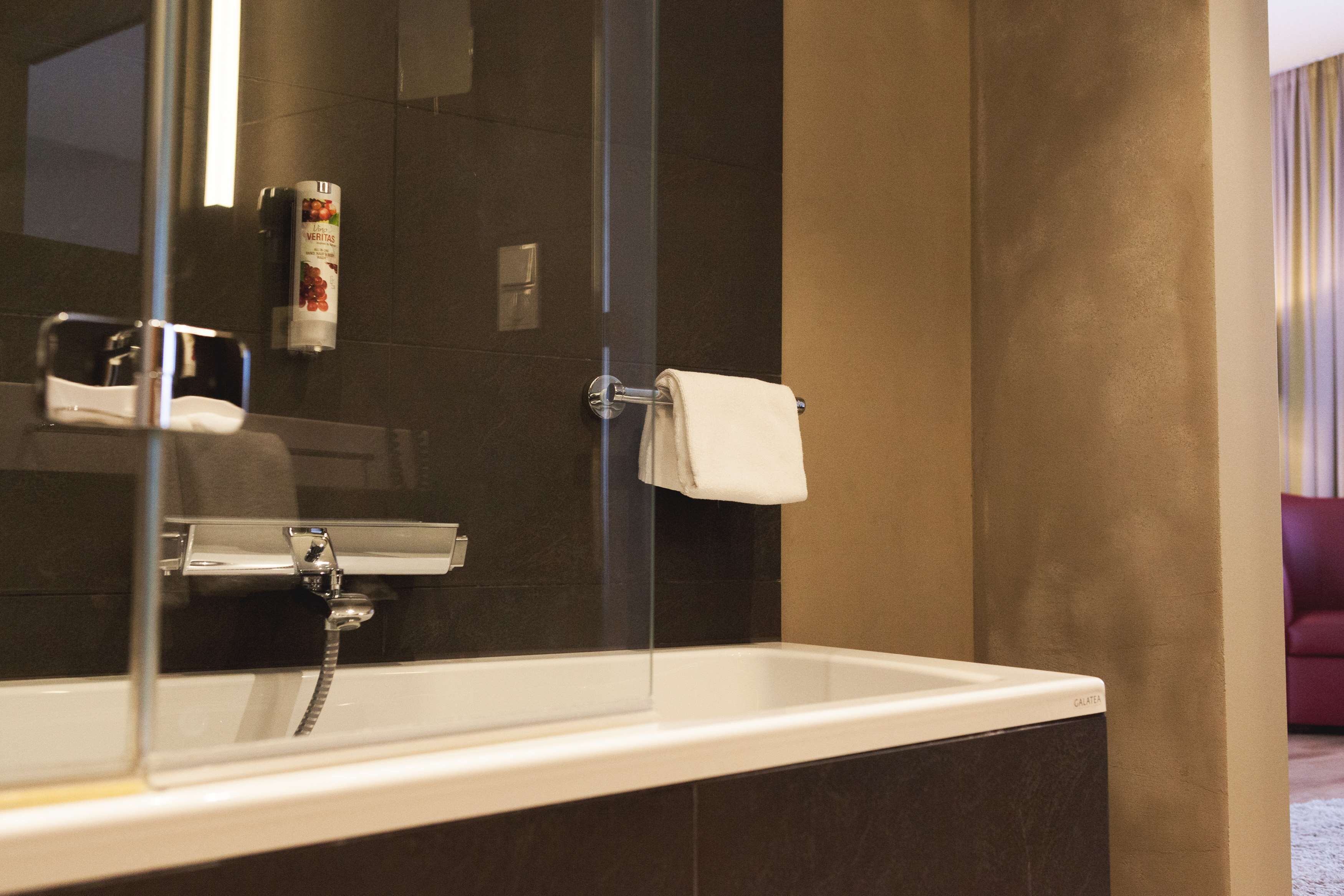 A bathroom with a bathtub, a towel rack, and a hand dryer.