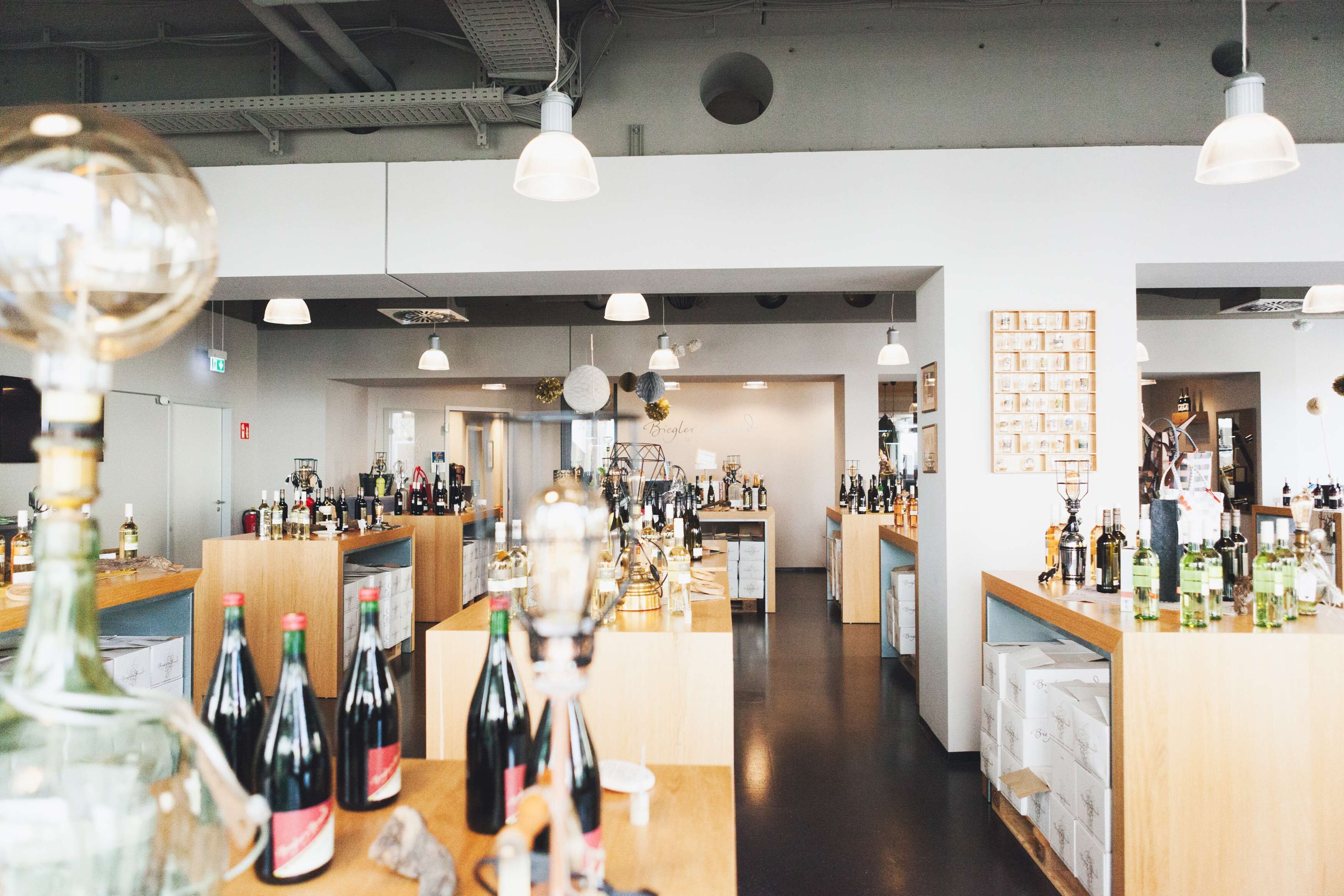 Una zona de bar con varias estanterías llenas de botellas, lámparas colgantes y una barra de madera.