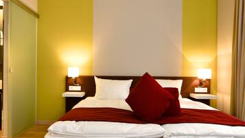A hotel room with a bed, two bedside tables, a nightstand, a bathroom with a sink, and a shower.