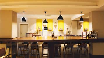 Een moderne keuken met een groot keukenblok, barstoelen, hanglampen en een wijnrek.