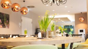 Comedor con una mesa de madera, sillas verdes y plantas en macetas.