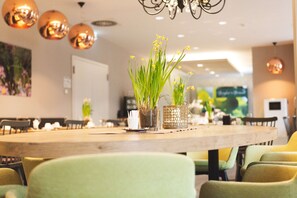 Comedor con una mesa de madera, sillas verdes y plantas en macetas.