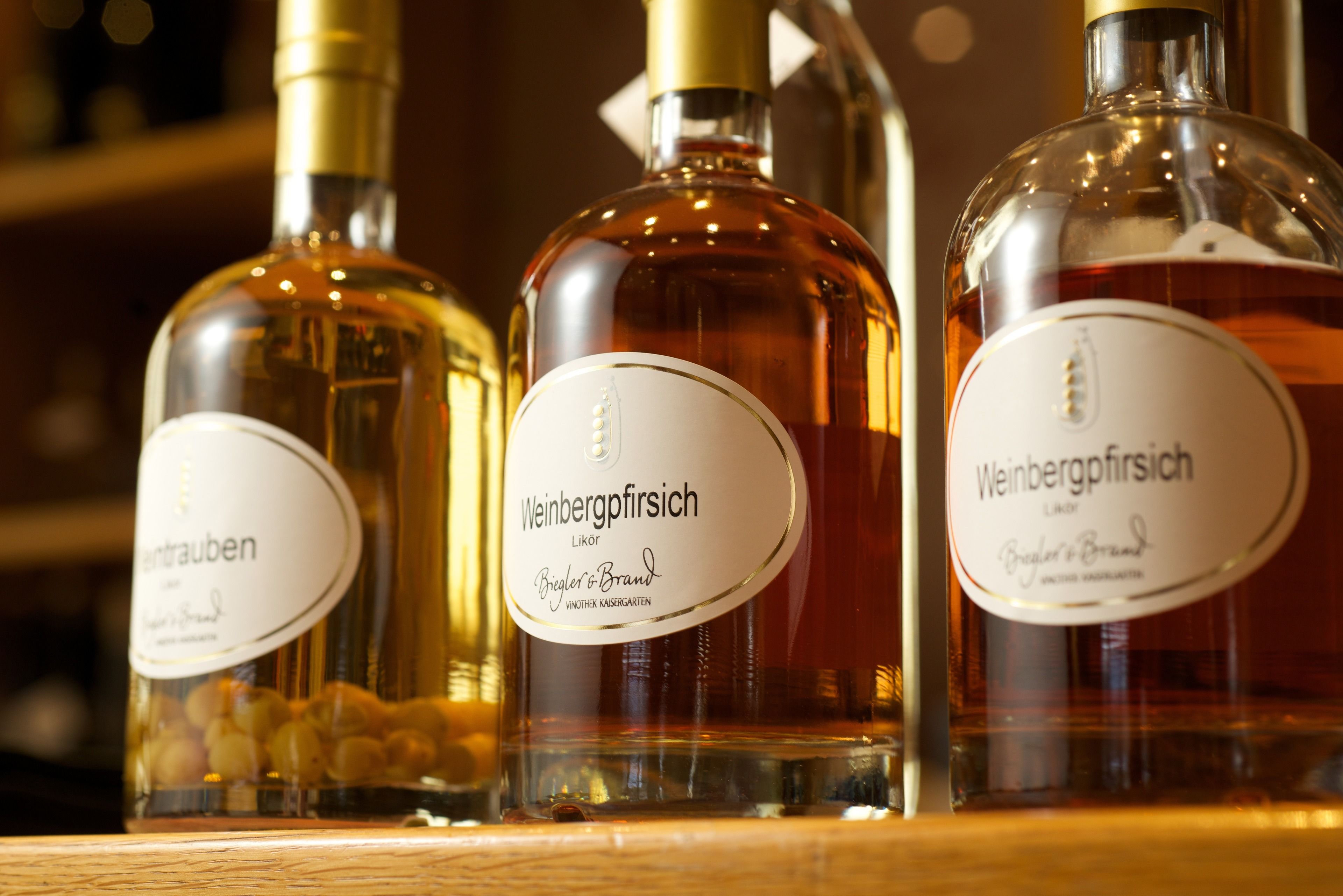 Three bottles of Weinbergpfrisch liquor on a wooden shelf.