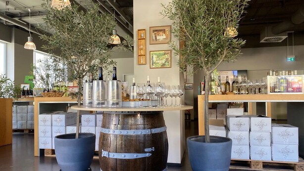 Una tienda de vinos con barricas de madera, botellas y copas.