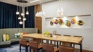 A modern dining area with a wooden table and brown chairs, a blue carpet, and a blue curtain backdrop.