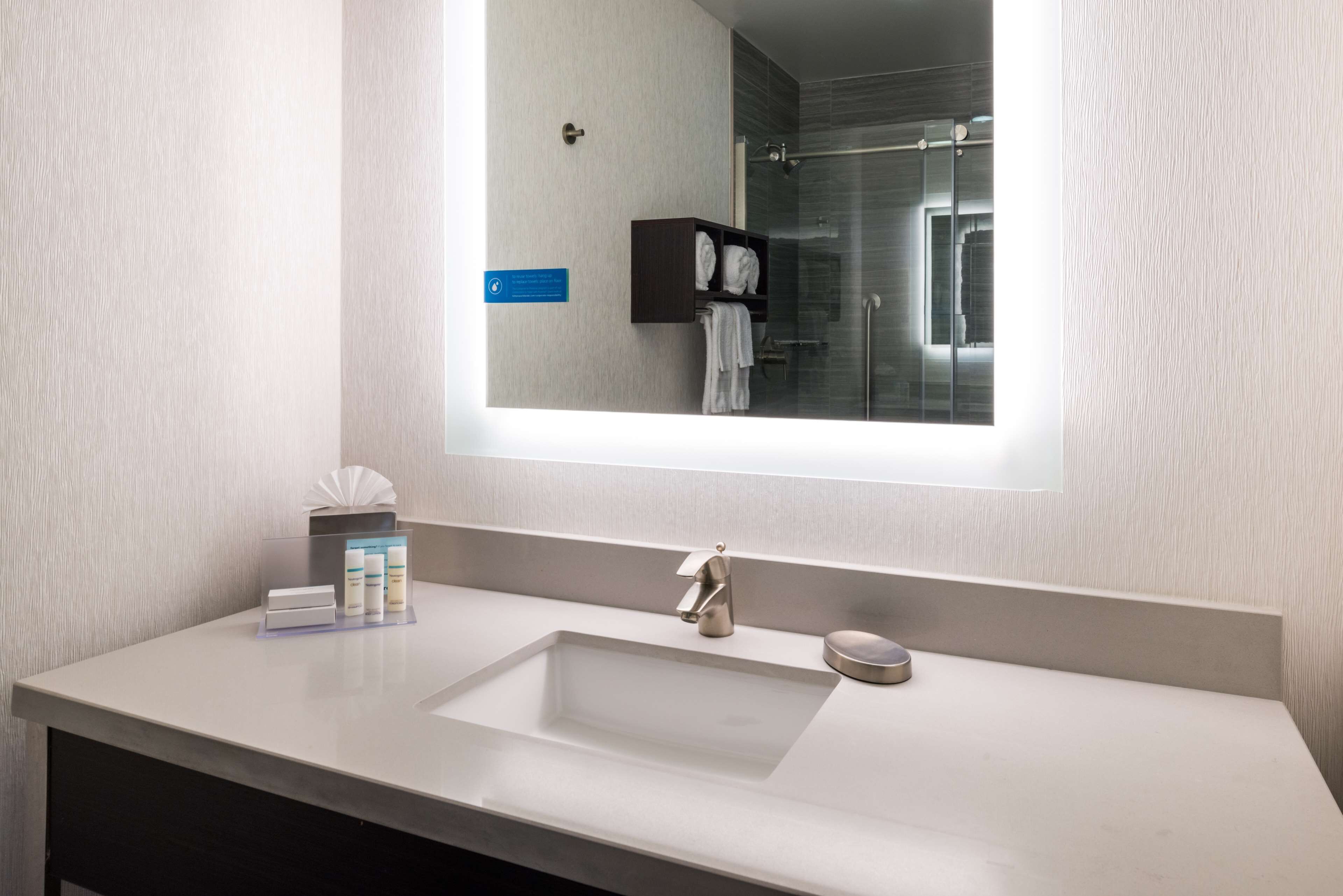 A modern bathroom with a large mirror, a rectangular sink, and a glass shower enclosure.