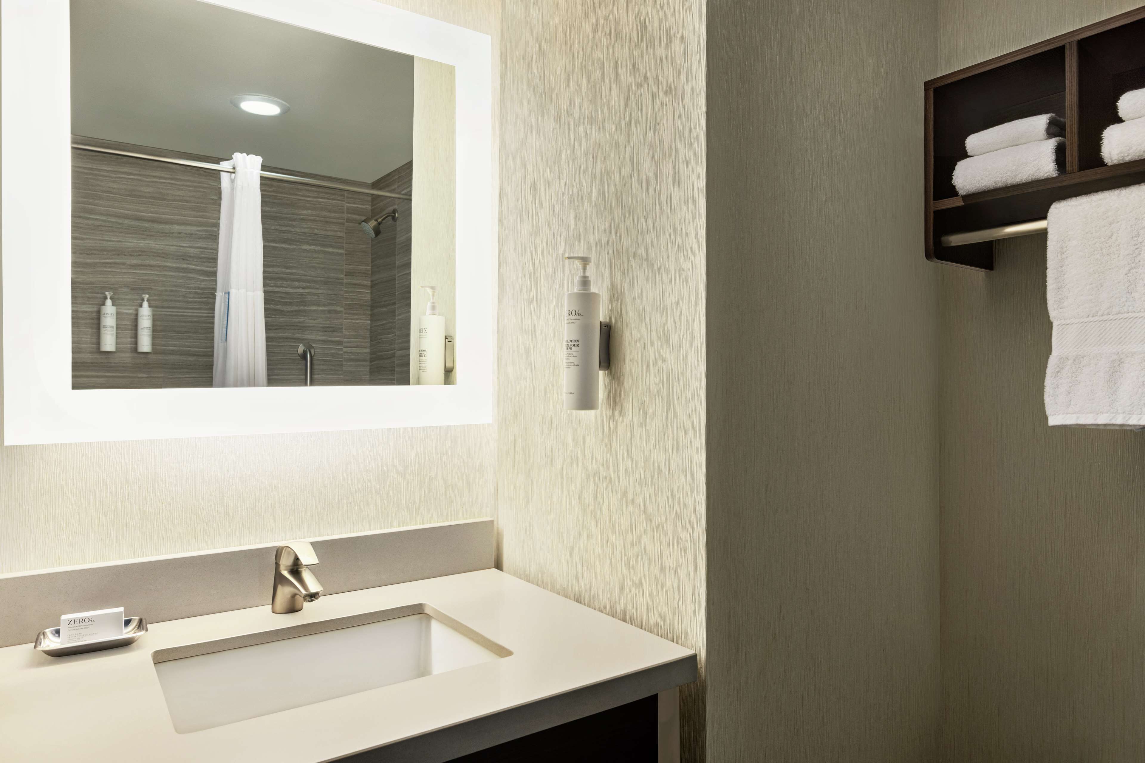 A modern bathroom with a large mirror, a sink, and a towel rack.