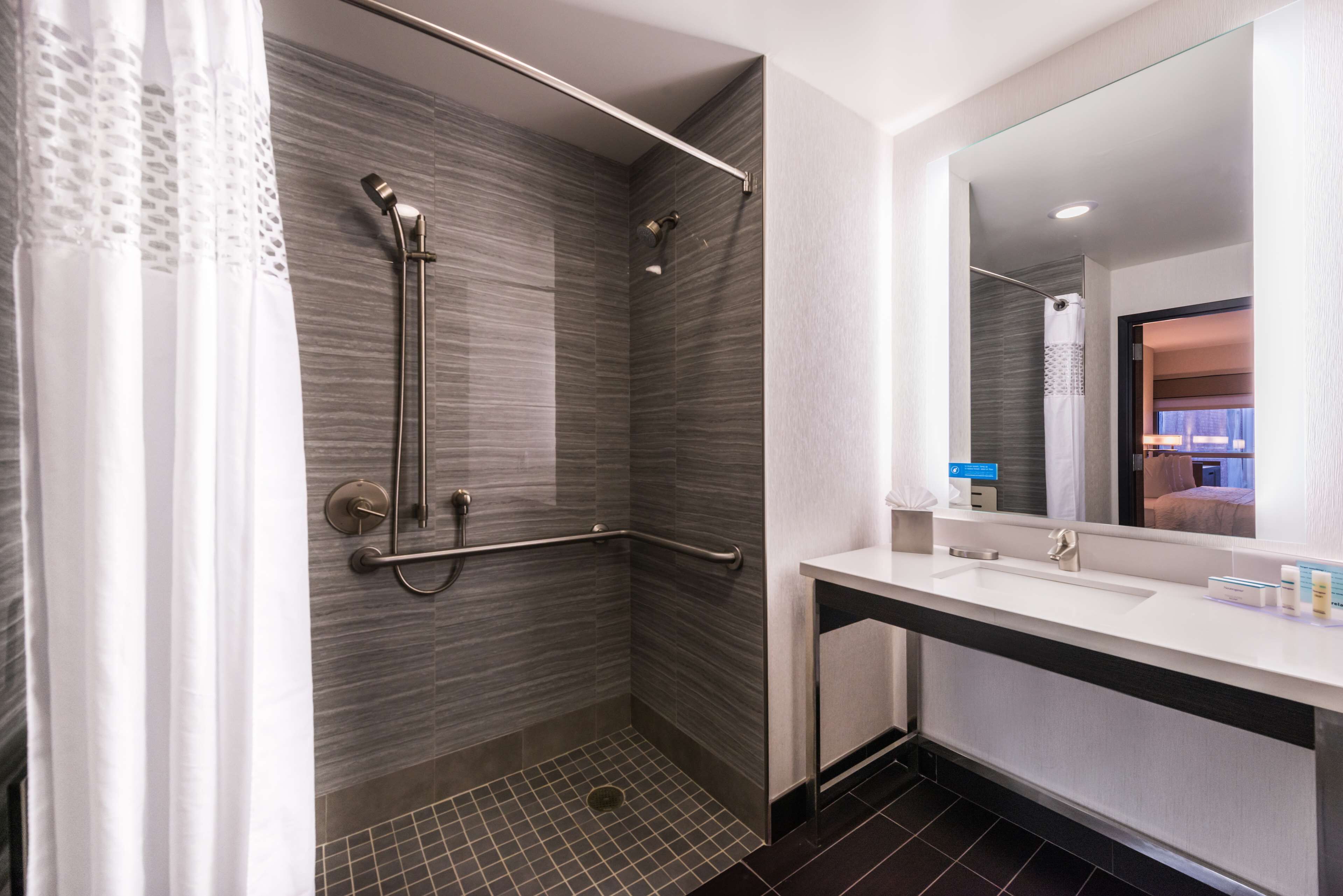 A modern bathroom with a shower, a sink, and a mirror.