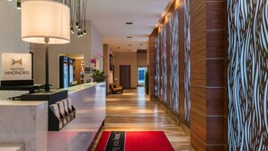 A hotel reception area with a marble counter, a large lamp, and a red carpet with text. - Hampton Inn San Francisco Downtown/Convention Center (San Francisco)