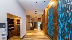 A hotel corridor with wooden flooring, a suite shop on the left, and a wall with a blue abstract pattern. - Hampton Inn San Francisco Downtown/Convention Center (San Francisco)