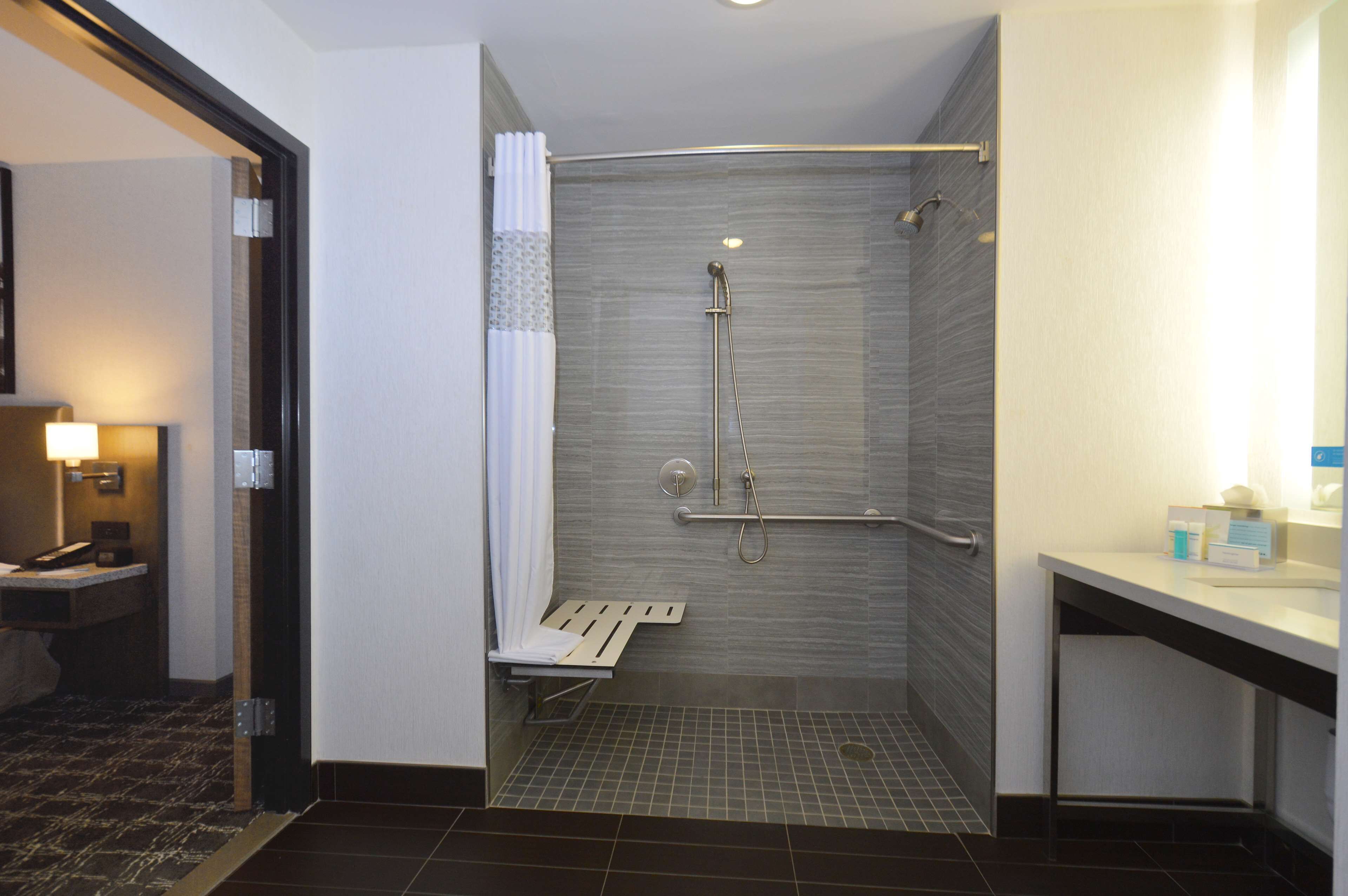 Une salle de bain moderne équipée d’une douche, d’un meuble-lavabo avec miroir et de toilettes.